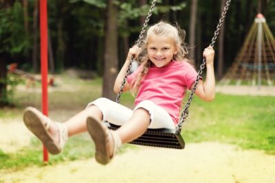 Happy girl swinging on playground. Transitions Made Easy for Children from Red Door Pediatric Therapy